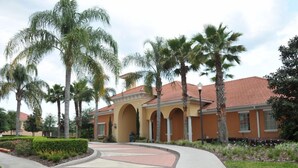 A building with a red-tiled roof, arched entryways, and palm trees in the foreground. - Solana #1 - 7 Bed Villa w/ Private Pool (Davenport)