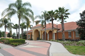 A building with a red-tiled roof, arched entryways, and palm trees in the foreground. - Solana #1 - 7 Bed Villa w/ Private Pool (Davenport)