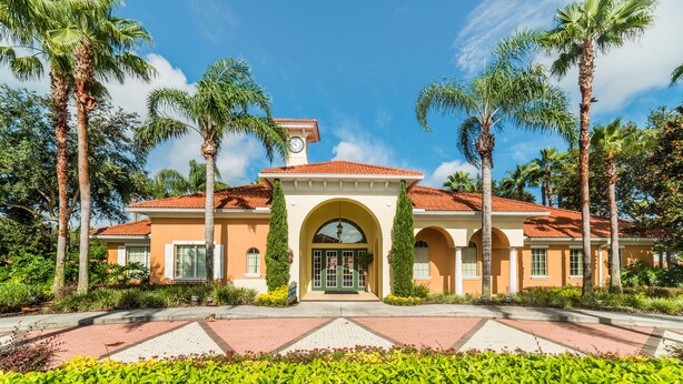 A two-story building with a red-tiled roof, a central arched entrance, and tall palm trees surrounding the property. - Solana #1 - 7 Bed Villa w/ Private Pool (Davenport)