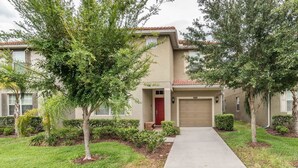 A two-story residential building with a beige exterior, a red door, and a garage. - Paradise Palms #2 - 6 Bed 5 Baths Villa (Kissimmee)
