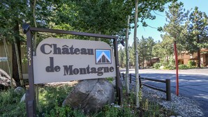 A sign for Chateau de Montague with a mountain icon, surrounded by greenery and rocks.