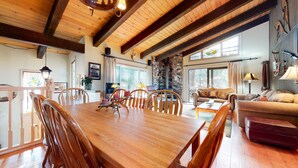 A spacious living area with a large wooden dining table surrounded by chairs, a cozy sofa, and a fireplace.
