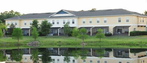 A multi-story hotel with a flat roof, large windows, and a reflection in a body of water.