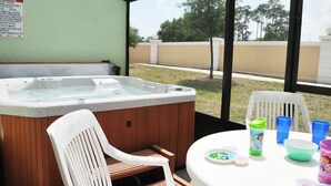 A hot tub in a covered outdoor area with a table and chairs, a sign with rules, and a view of a fence and trees. - Shv1173ha - 4 Bedroom Townhome In Coral Cay Resort, Sleeps Up To 10, Just 6 Miles To Disney (Kissimmee)