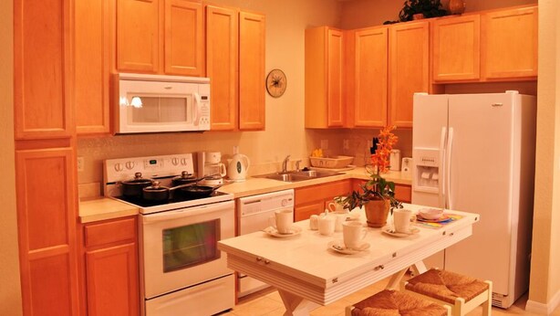 A kitchen with wooden cabinets, a microwave, stove, dishwasher, and a refrigerator. - Shv1173ha - 4 Bedroom Townhome In Coral Cay Resort, Sleeps Up To 10, Just 6 Miles To Disney (Kissimmee)