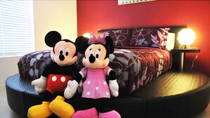 Ein Bett mit Mickey Maus und Minnie Maus Stofftieren auf einer runden Plattform.