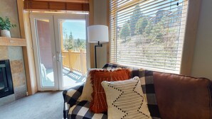 Ein gemütliches Wohnzimmer mit einer Couch, einem Kamin und Blick durch eine Schiebetür.
