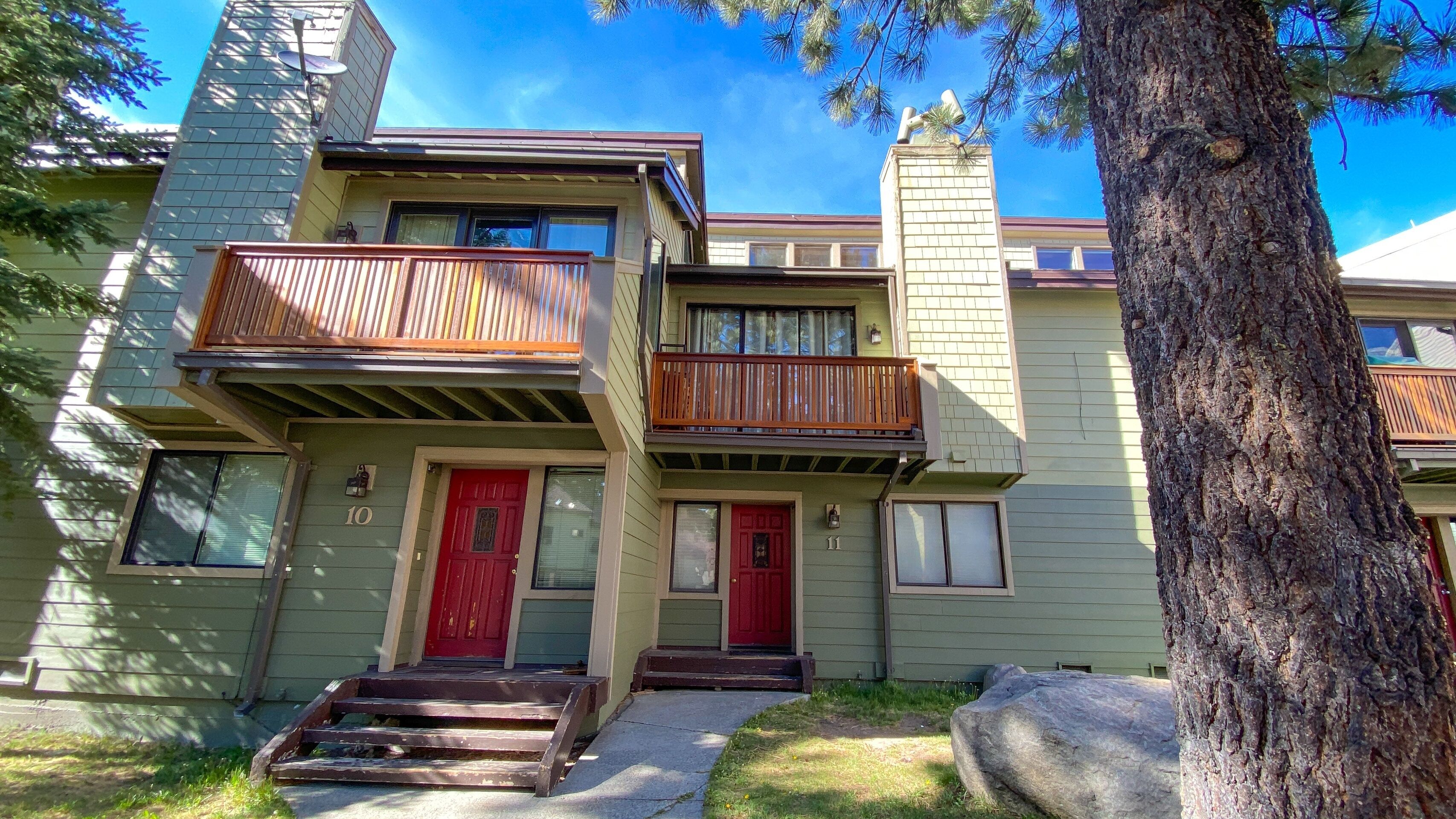 A two-story building with a red door, a balcony, and a chimney.