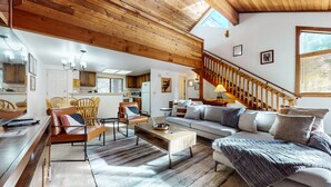 A spacious living area with a wooden ceiling, a sofa set, a dining table, and a kitchen in the background. - Mammoth Sierra Townhome (Mammoth Lakes)