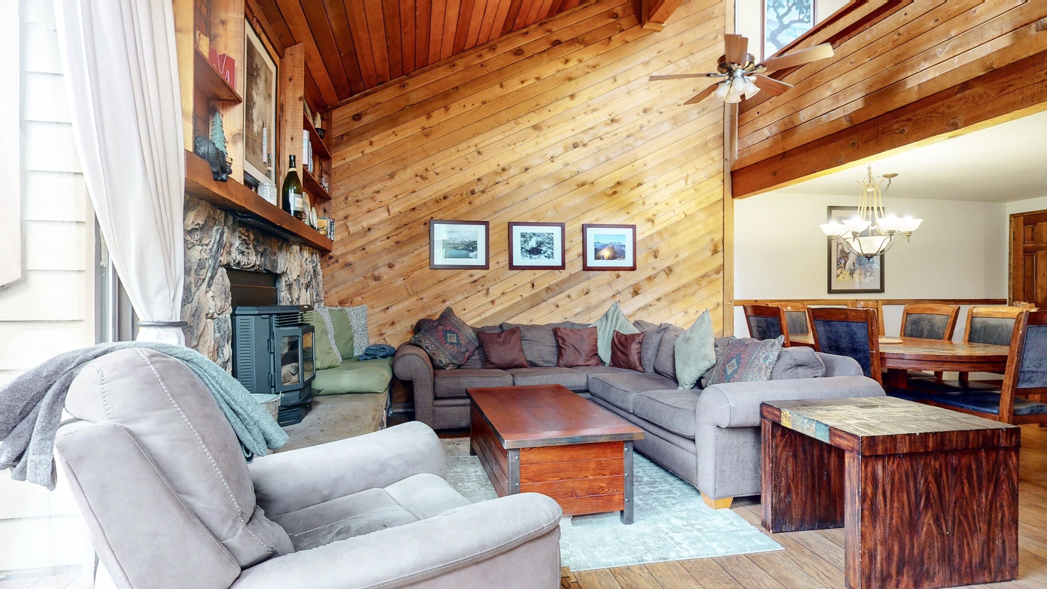 A cozy living room with a fireplace, wooden walls, and a dining area with wooden furniture.