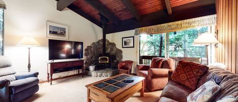 A cozy living room with a stone fireplace, a television, and comfortable seating.