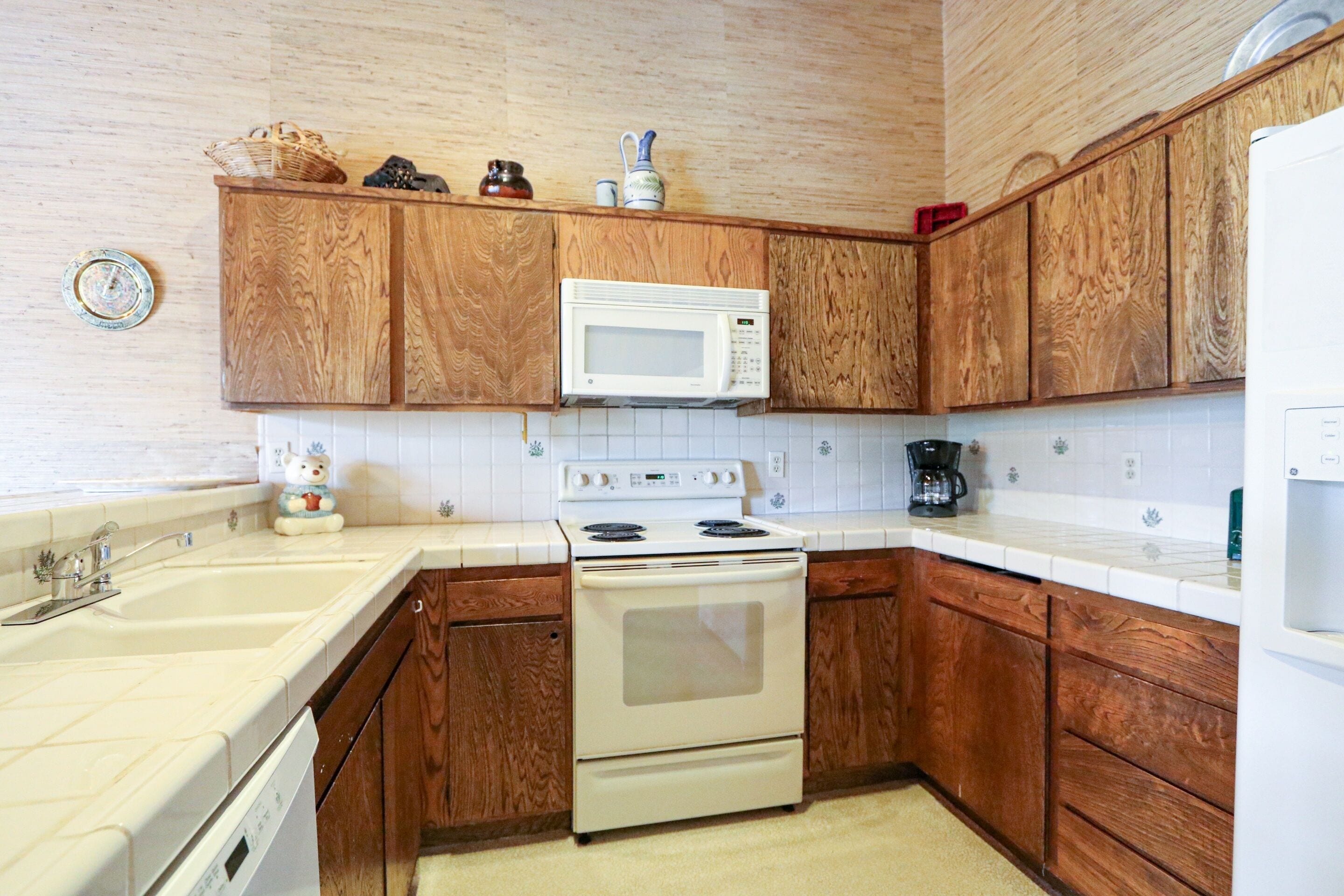 A kitchen with wooden cabinets, a white microwave, a stove, and a sink.