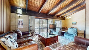 Ein gemütliches Wohnzimmer mit einem Ledersofa, einem Glastisch und einer Holzbalkendecke.