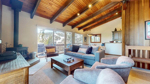 A cozy living room with a fireplace, a sofa, a coffee table, and a view of the outdoors.