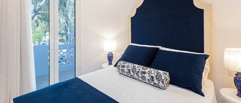 Un dormitorio con una cama grande, un cabecero decorativo y vistas a través de un ventanal.