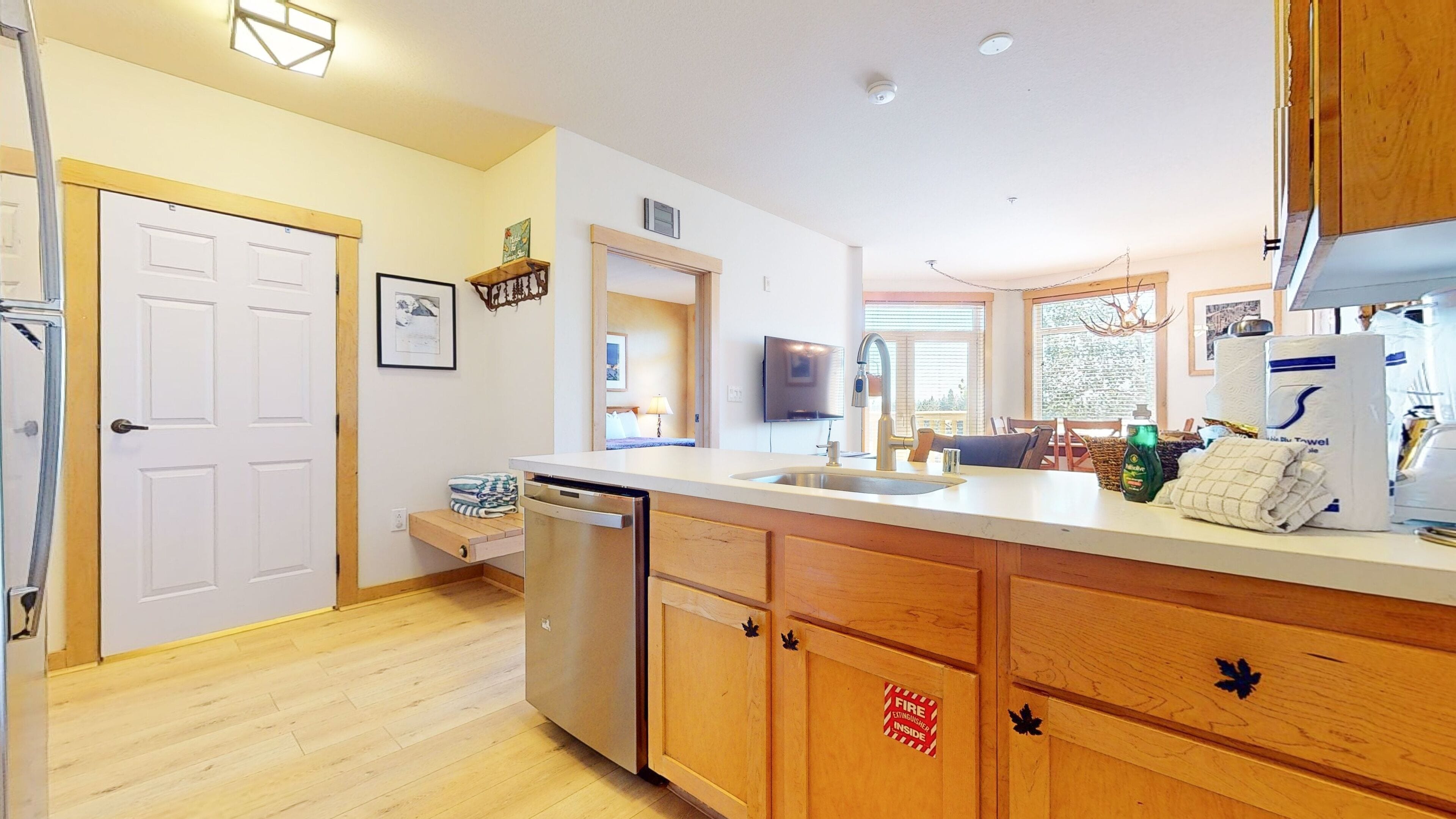 A modern kitchen with wooden cabinets, a stainless steel dishwasher, and a large island with a sink.