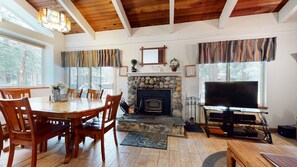 A cozy living room with a stone fireplace, wooden dining table, and a television. - Horizons 4 188 Cozy Condo with Great Complex Amenities, On the Shuttle Route by RedAwning (Mammoth Lakes)