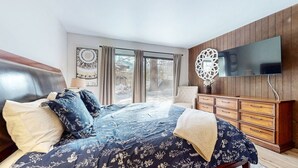 A bedroom with a large bed, a wooden dresser, a television, and a window with a view of the outside. - Chateau de Montagne 17 Spacious Family Townhome with Great Complex Amenities On Shuttle Route by RedAwning (Mammoth Lakes)