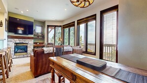 Un salón espacioso con chimenea, ventanas amplias y una mesa de comedor de madera.
