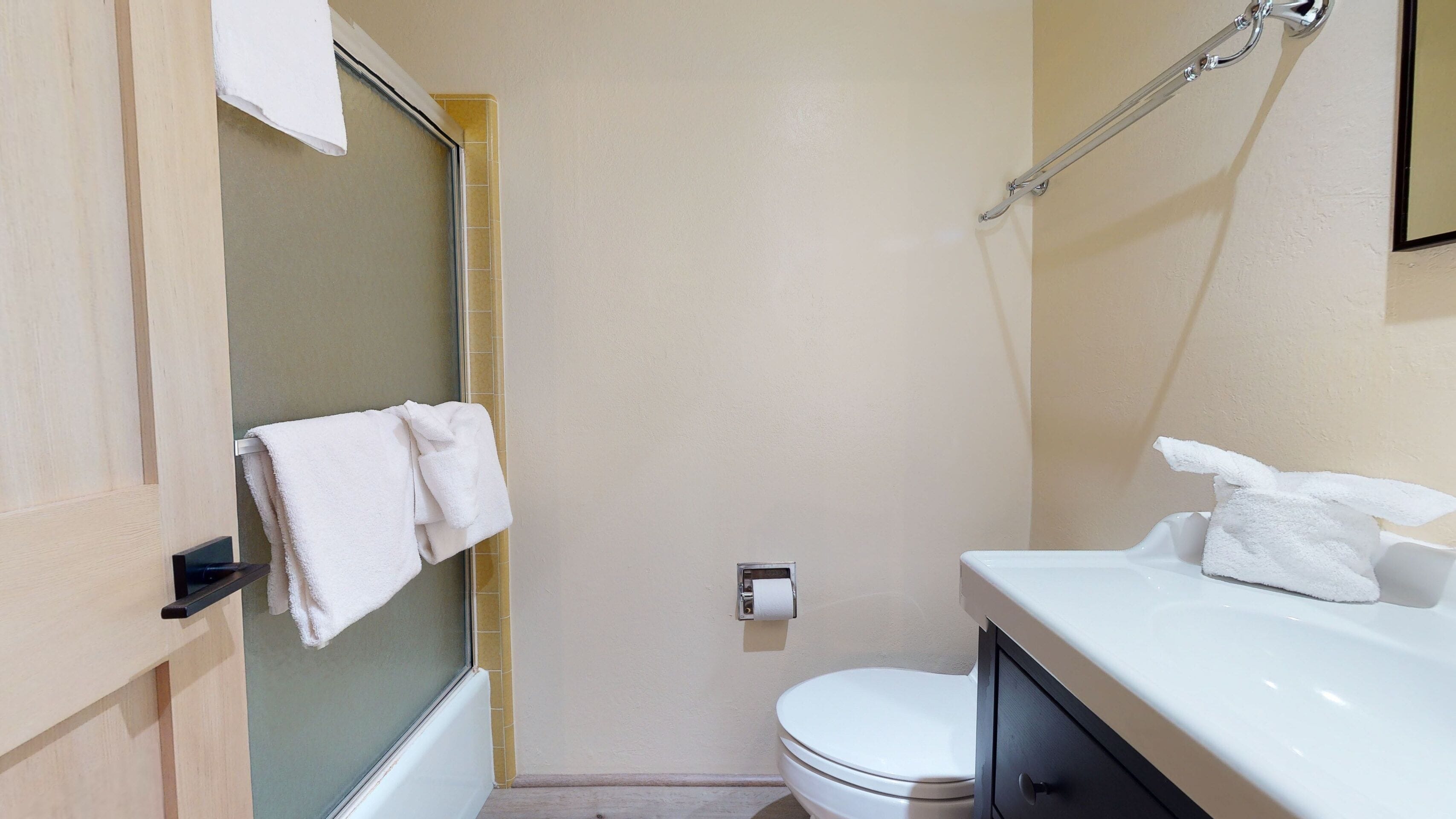 A small, clean bathroom with a toilet, a sink, and a shower.