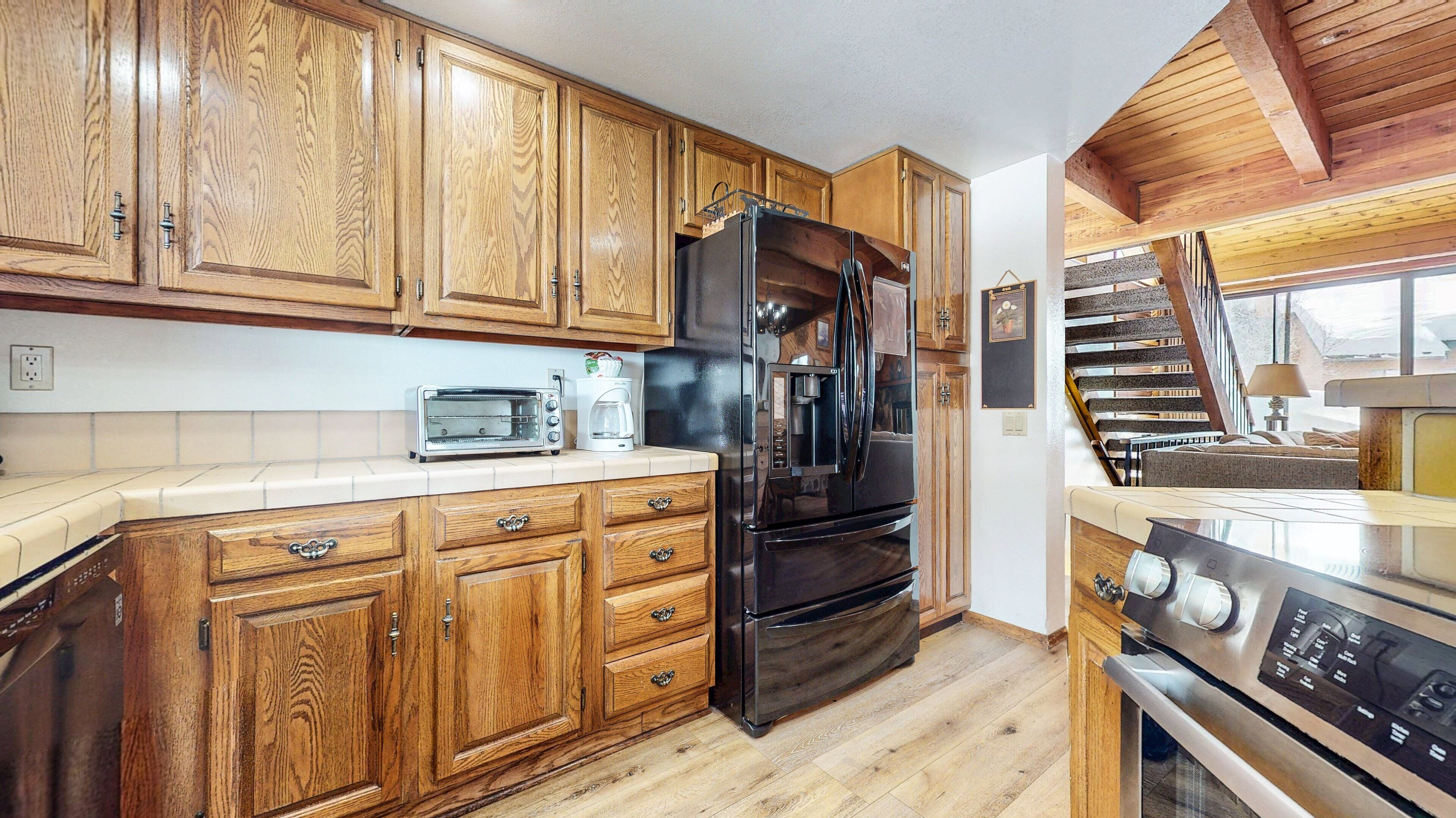 A kitchen with wooden cabinets, a black refrigerator, a toaster, and a stove.