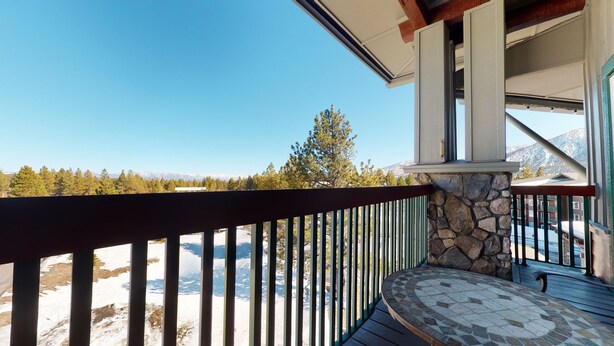 A balcony with a stone wall and a view of a snowy mountain range. - Juniper Springs Lodge 539 Deluxe Condo Great Complex Amenities near Ski-In Ski-Out by RedAwning (Mammoth Lakes)
