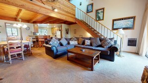 Ein geräumiges Wohnzimmer mit einer großen Sofagarnitur, einem Couchtisch und einer Treppe, die in ein Obergeschoss führt.