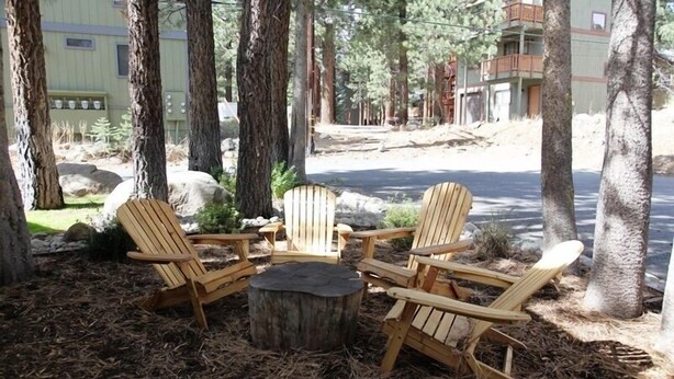 A wooden deck with Adirondack chairs and a central fire pit surrounded by trees. - St. Moritz 12 Bright and cozy Mountain Cabin, Centrally Located by RedAwning (Mammoth Lakes)