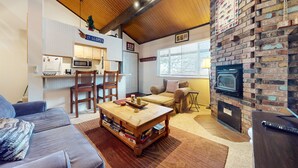 Uma sala de estar acolhedora com lareira, área de jantar com cadeiras, um sofá e uma mesa de centro com jogos de tabuleiro.