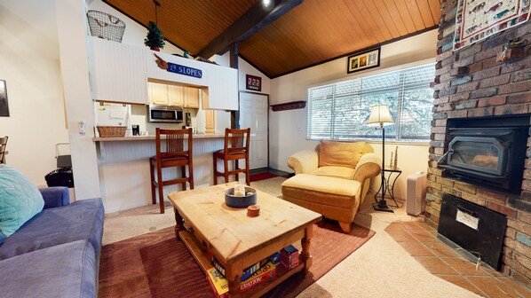 A cozy living room with a fireplace, a dining area with a microwave, and a sofa. - Sierra Manors 75 Cozy and Comfy Condo, On the Shuttle Route by RedAwning (Mammoth Lakes)