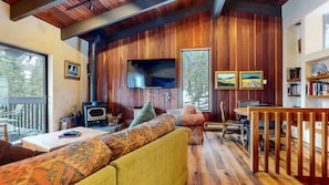 A cozy cabin interior with a wooden interior, a fireplace, a television, and a dining area. - Mammoth West 143 Quiet Condo With Amazing Mountain Views and A Short Walk to Canyon Lodge by RedAwning (Mammoth Lakes)
