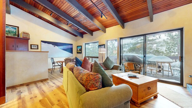 A spacious living area with a wooden ceiling, large windows, and a cozy seating arrangement. - Mammoth West 143 Quiet Condo With Amazing Mountain Views and A Short Walk to Canyon Lodge by RedAwning (Mammoth Lakes)