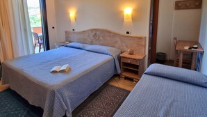 Quarto de hotel com duas camas, cabeceira de madeira, mesas de cabeceira, uma mesinha e ar condicionado fixado na parede.