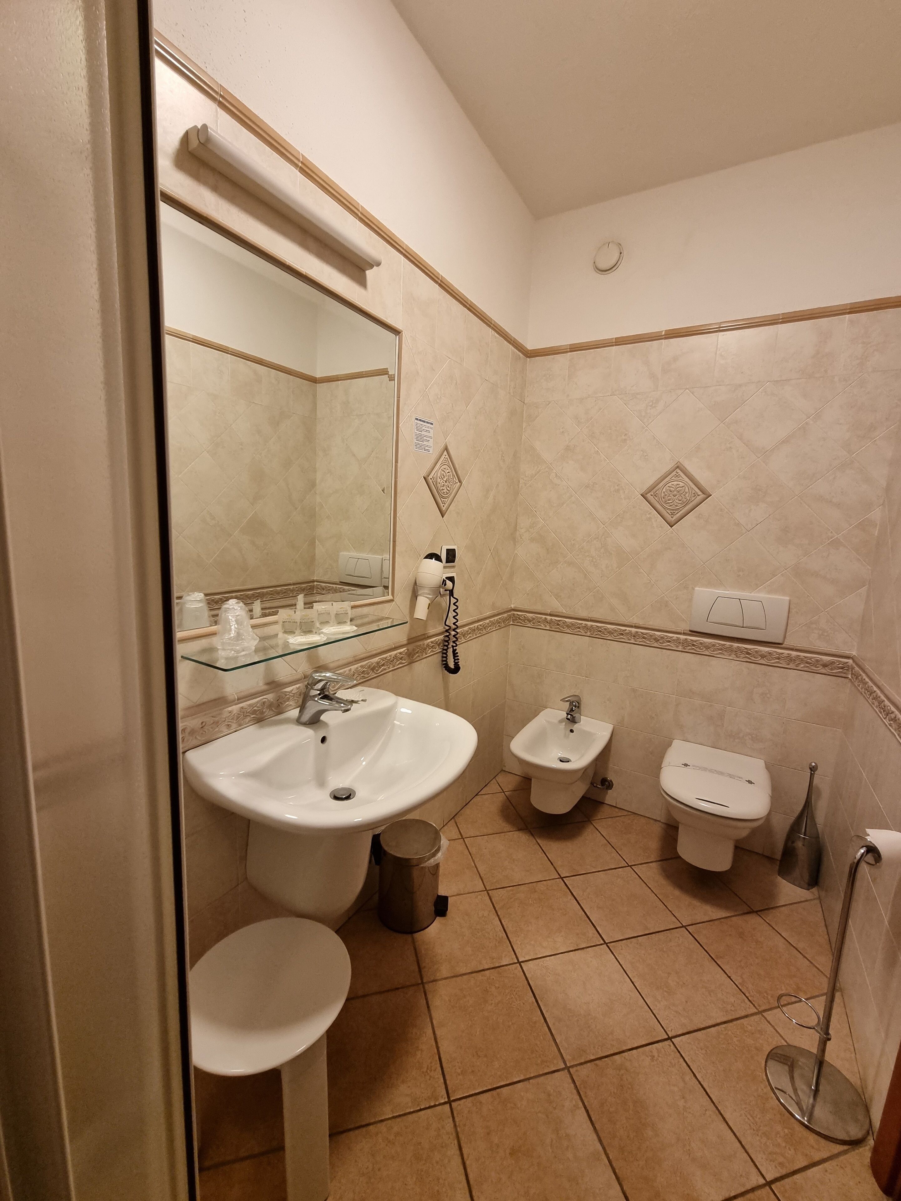 Une salle de bain comprenant un lavabo, deux toilettes, un bidet et un miroir.