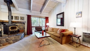 Una sala acogedora con chimenea de piedra, un sofá, una mesa de centro y una lámpara.