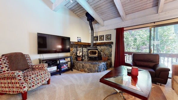 Una sala de estar con chimenea de piedra, televisor de pantalla plana, sofá y una mesa de centro.