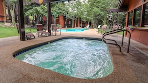 Un área de jacuzzi con piscina, rodeada de sillas de descanso y un porche cubierto.