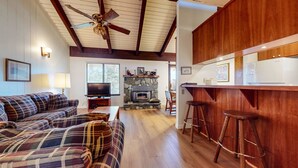 A living room with a plaid sofa, a television, and a stone fireplace. - Discovery 4 104 Pet-Friendly Rustic Mountain Cabin, Close to Canyon Lodge by RedAwning (Mammoth Lakes)