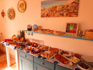 Ein reich gedeckter Buffet mit verschiedenen Speisen und ein Gemälde einer Küstenstadt an der Wand.