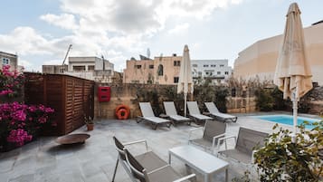 Una piscina al aire libre, sombrillas, sillones reclinables de piscina