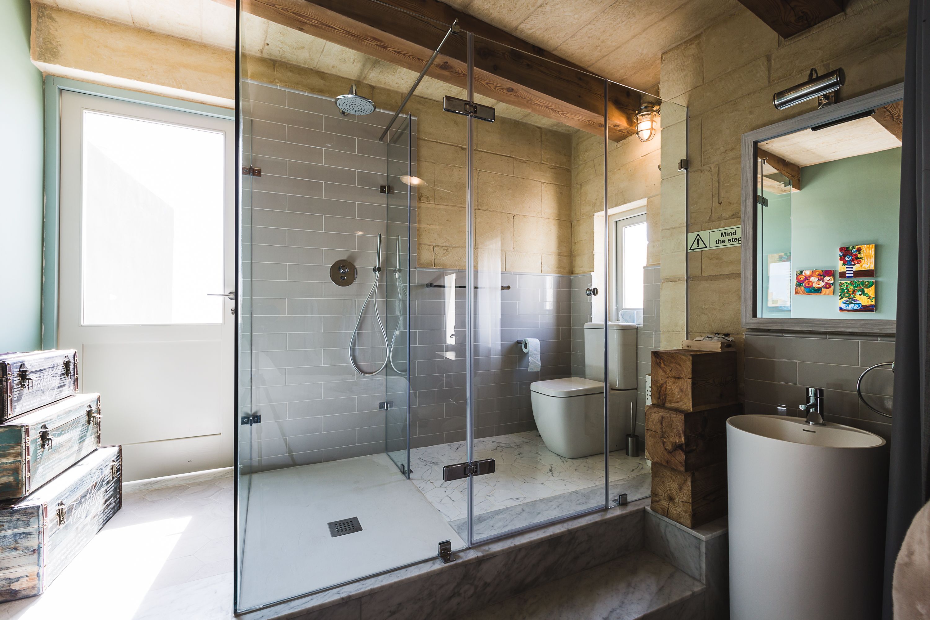 A modern bathroom with a glass-enclosed shower, a toilet, and a sink.