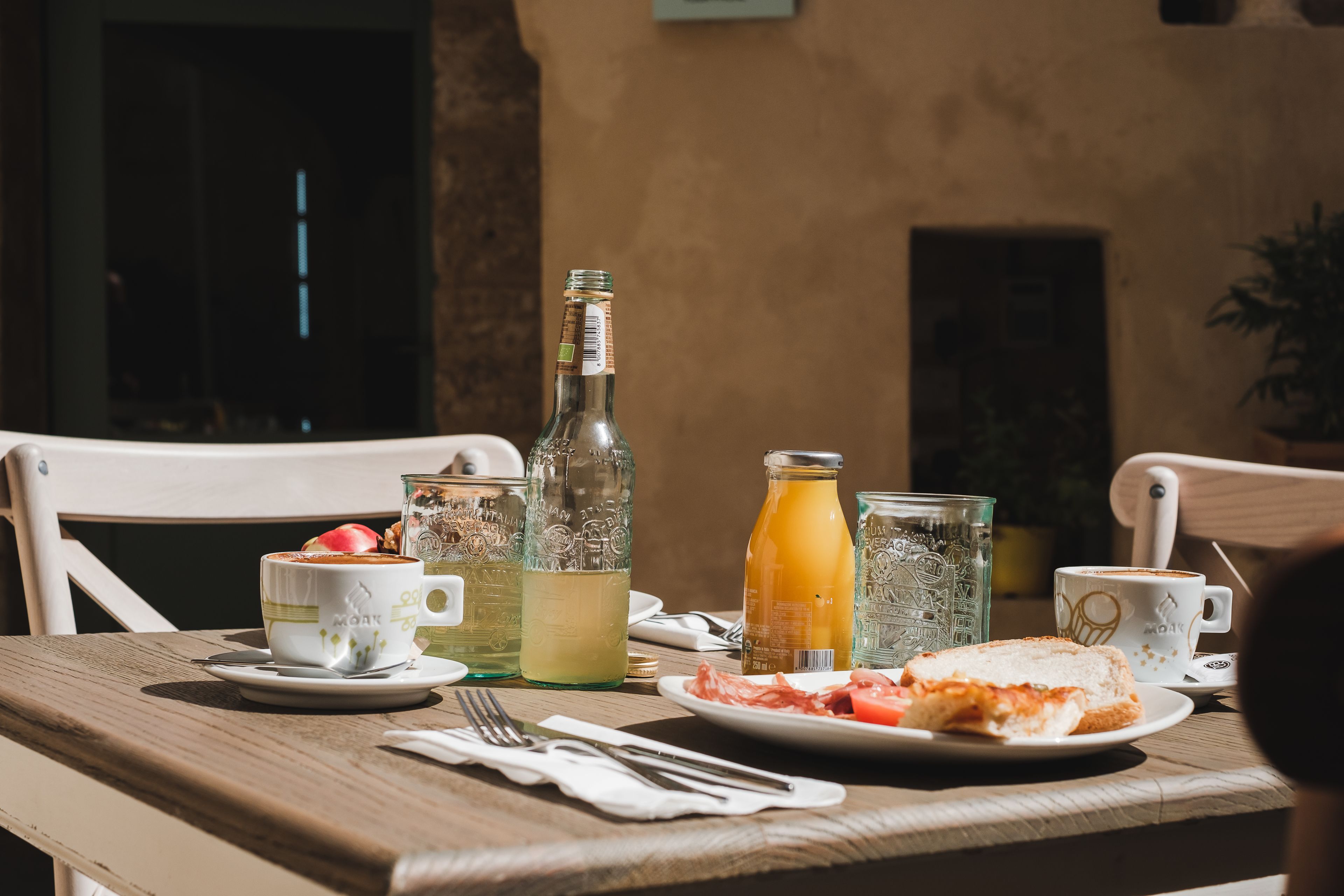 A table set with a plate of food, a glass of orange juice, and a bottle of water.