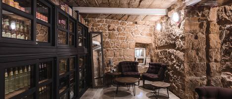 A stone-walled room with a wooden bookshelf, two armchairs, and a small round table.