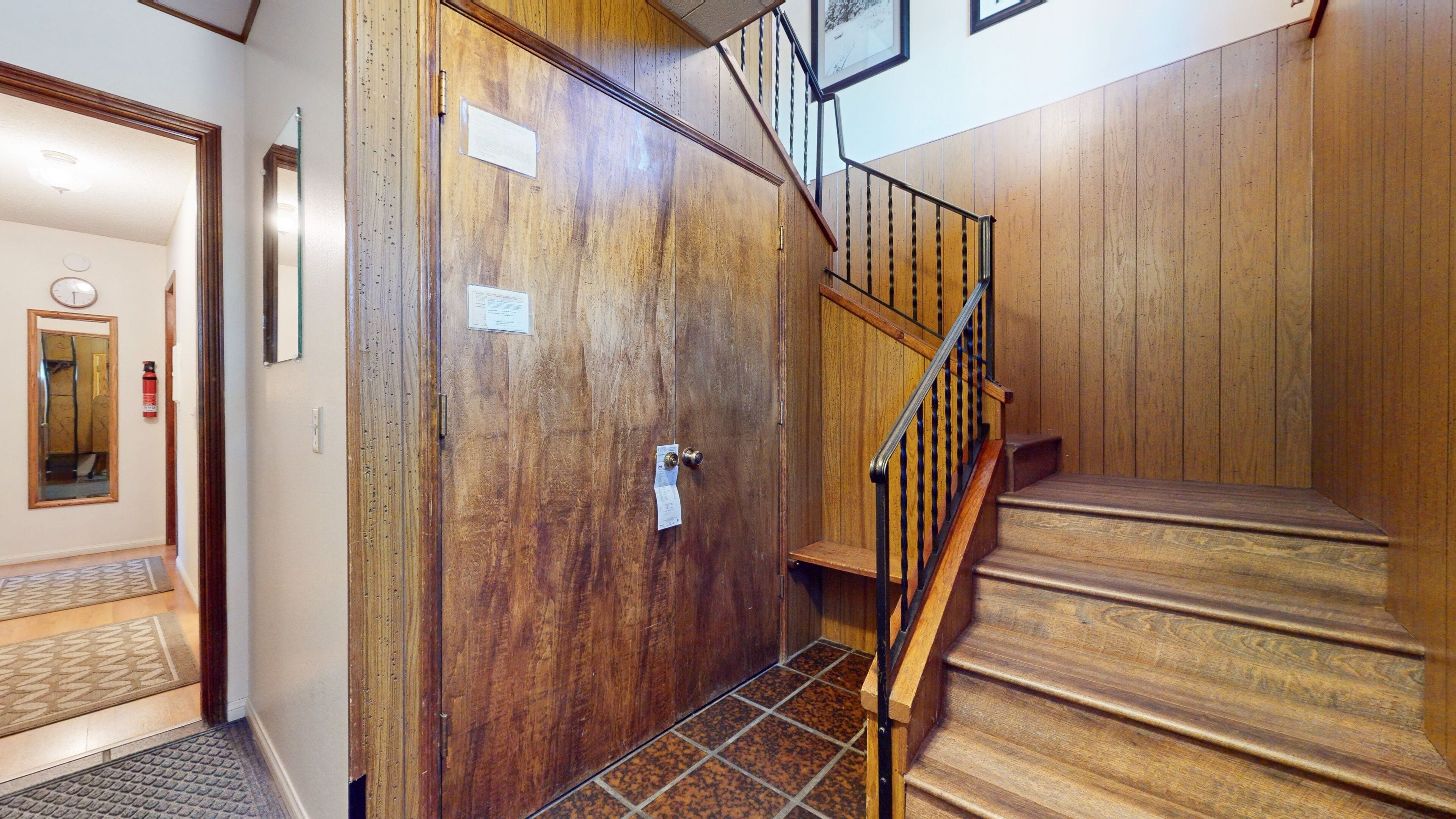 Un escalier en bois avec une rampe métallique menant à un palier.