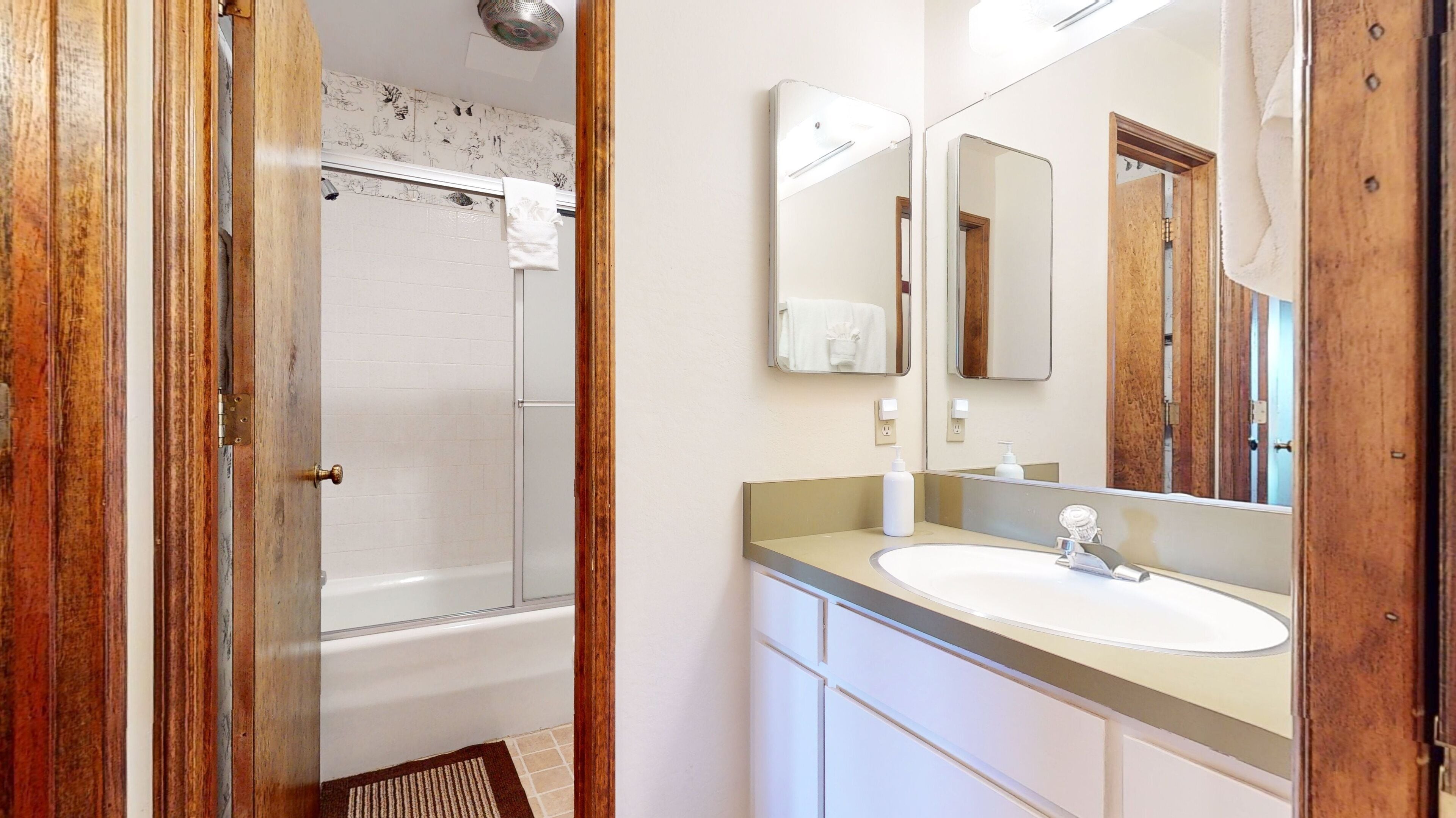 A bathroom with a bathtub, a sink, and a mirror.