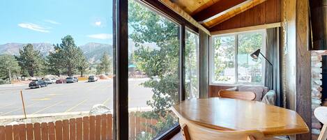 A wooden dining area with a large window overlooking a parking lot and mountains.