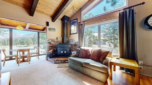 Una sala de estar acogedora con chimenea, un sofá y un comedor con sillas.