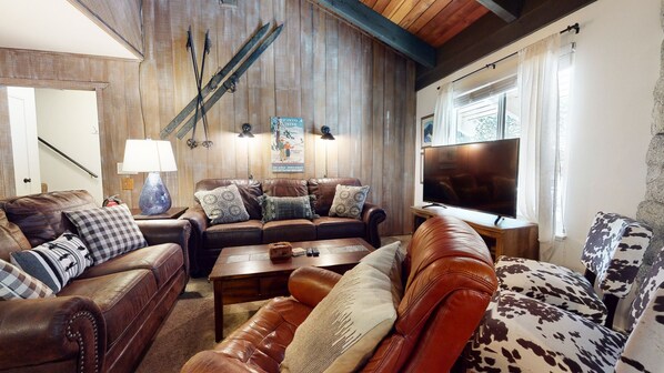 A cozy living room with leather sofas, a coffee table, and a television.
