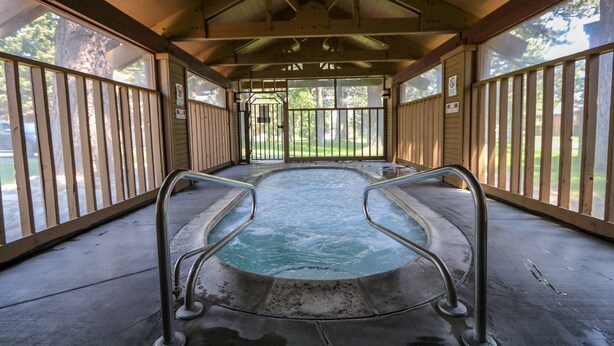 A covered hot tub area with metal railings and a concrete floor.