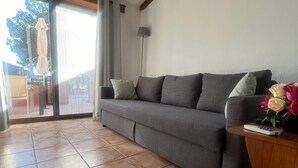 Una sala de estar con un sofá gris, una mesita de madera y una lámpara de pie.